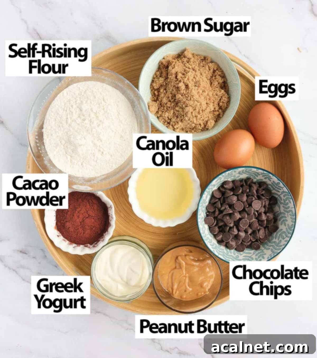 A collection of fresh ingredients for baking Double Chocolate Peanut Butter Muffins, neatly arranged on a round wooden tray.