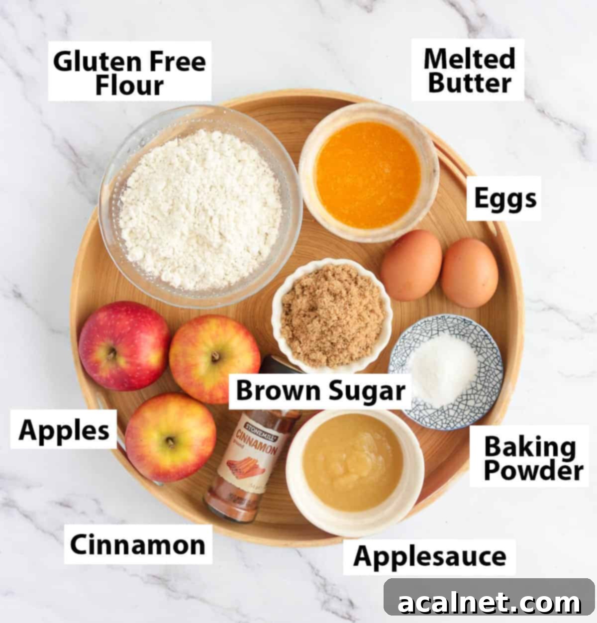 Effortless Gluten-Free Apple Cake 3 Various ingredients for gluten-free apple cake, including apples, eggs, butter, sugar, and flour, neatly arranged on a round platter.