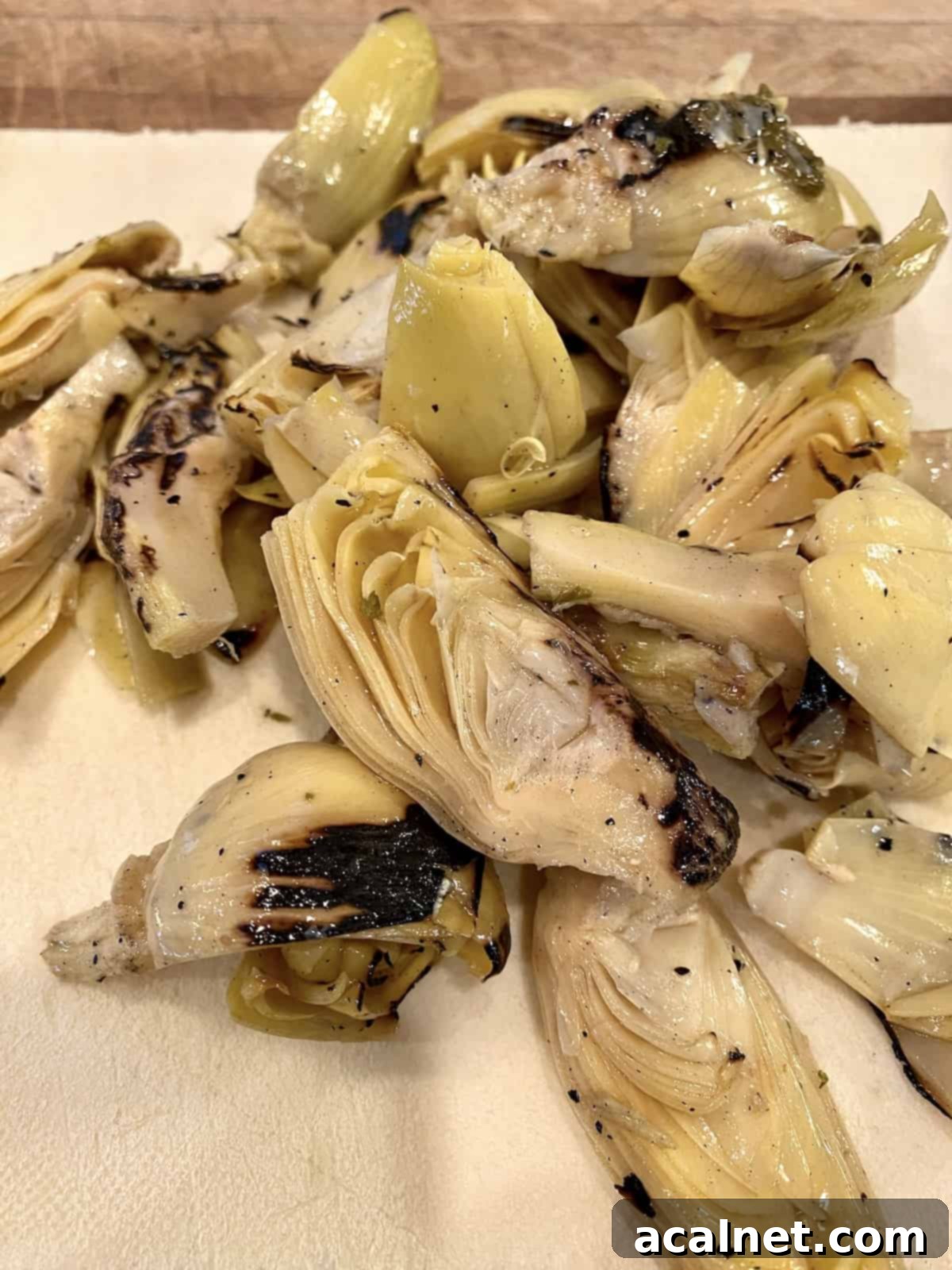 Marinated artichoke hearts displayed on a cutting board, ready for chopping.
