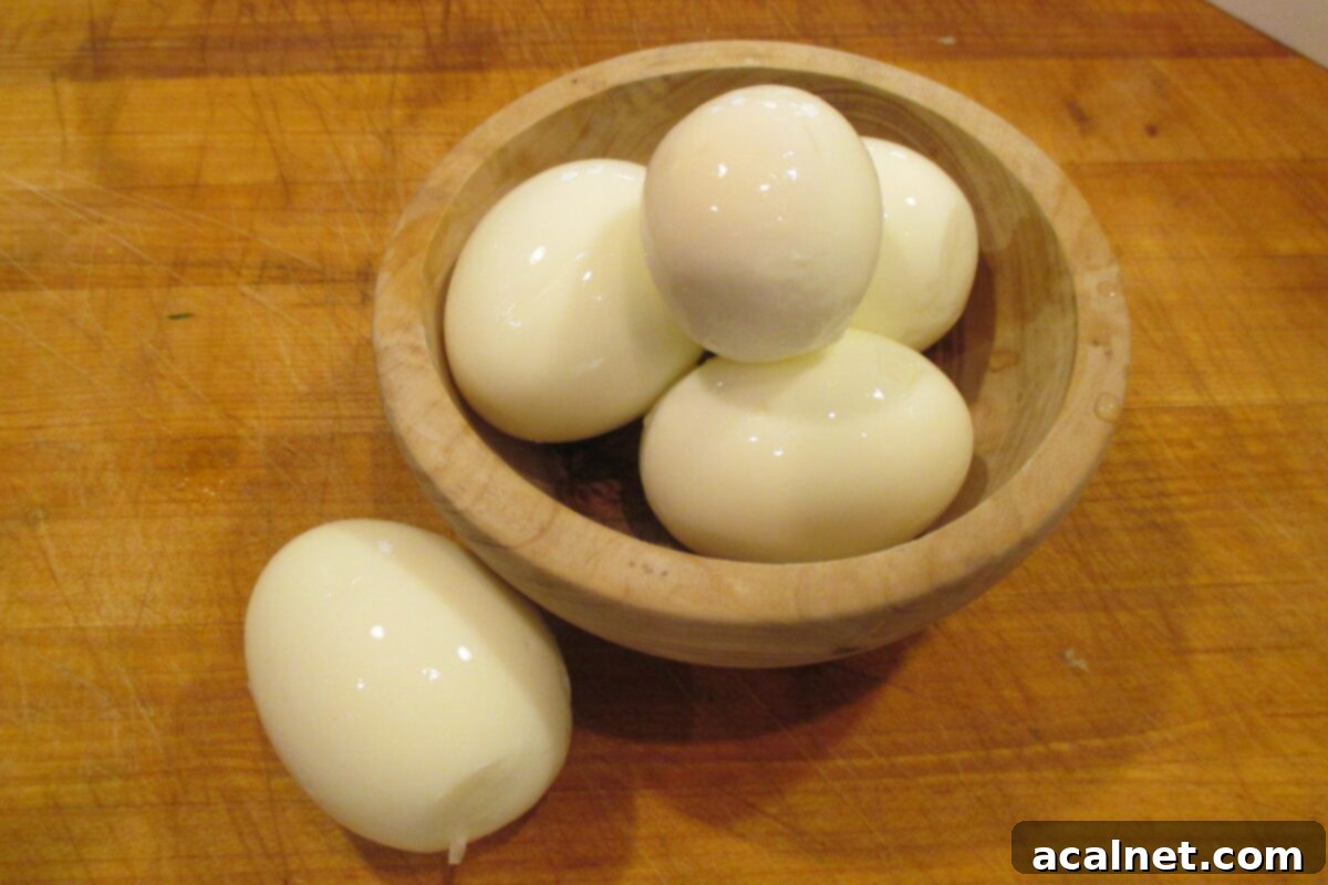 Several hard-boiled eggs in a rustic wooden bowl, ready to be prepared for the potato salad.