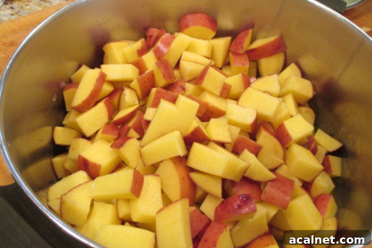 Diced red potatoes simmering in a pot of salted water on the stove, cooking to tender perfection.