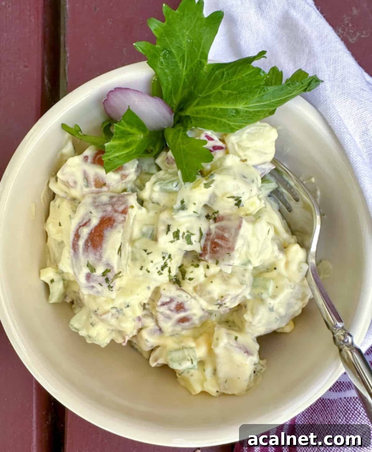 A small serving bowl filled with creamy red potato salad, with a fork resting gracefully on the side, ready to be enjoyed.