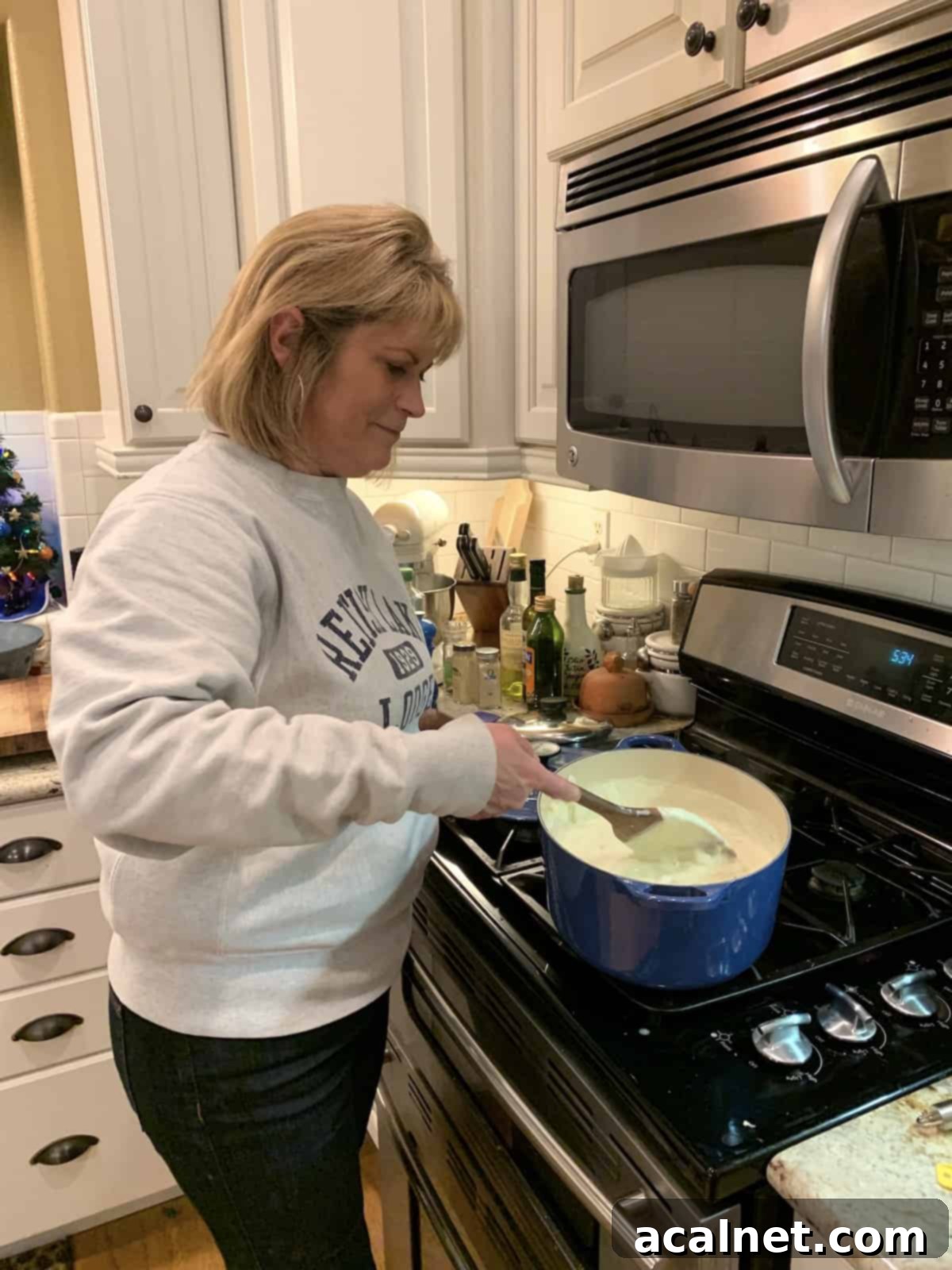 A person named Melinda stirring a pot of creamy clam chowder on the stove, ensuring all ingredients are well combined.