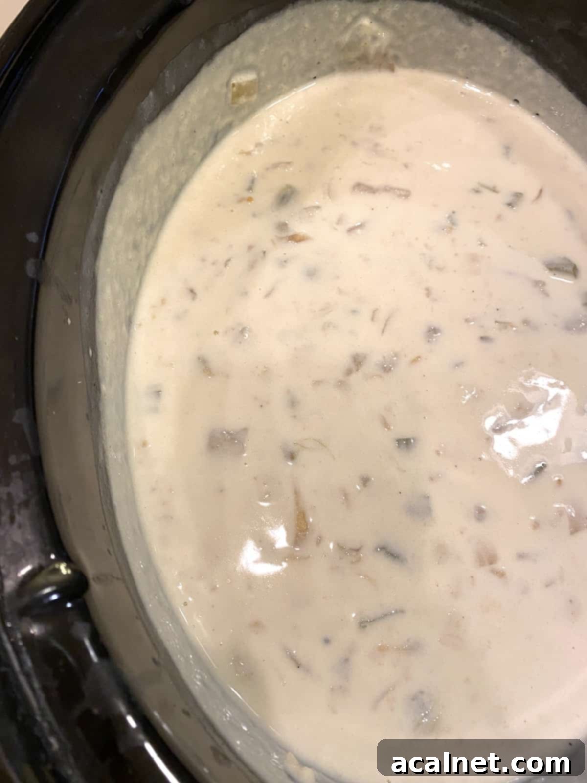 A hearty and creamy clam chowder simmering gently in a crockpot, showcasing its rich texture and inviting warmth.