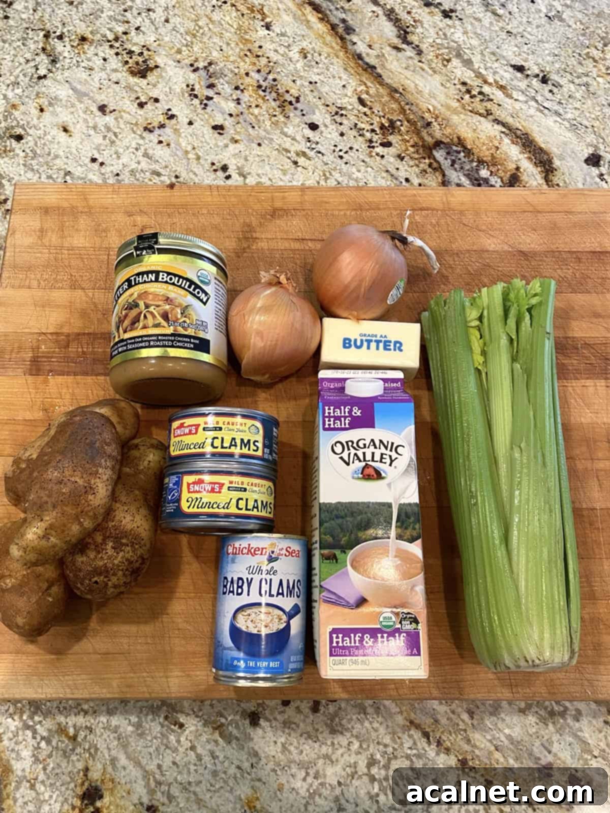 Fresh ingredients for homemade clam chowder laid out neatly on a wooden cutting board, including potatoes, celery, and onions.