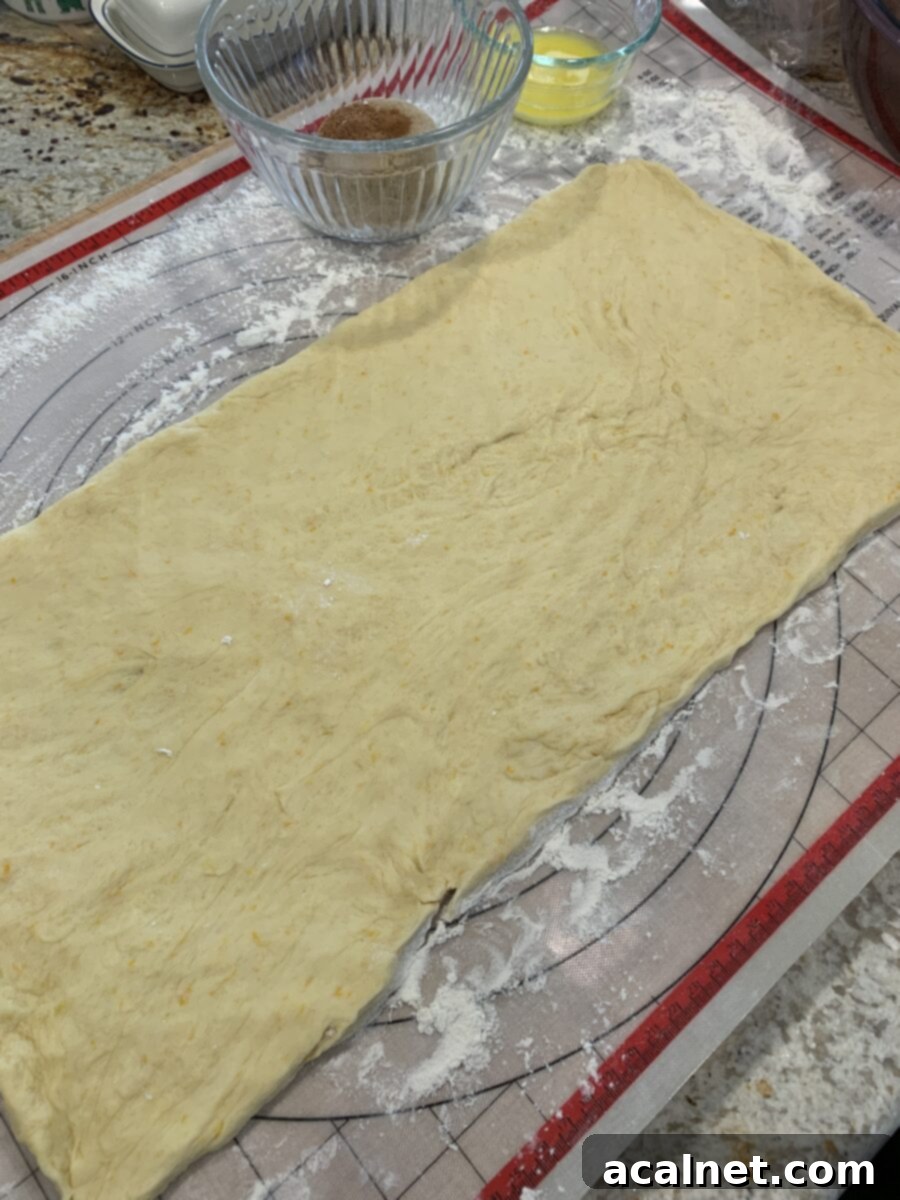 Sweet roll dough, perfectly kneaded and risen, is shown rolled out into an even rectangular shape on a silicone pastry mat, ready for the filling.