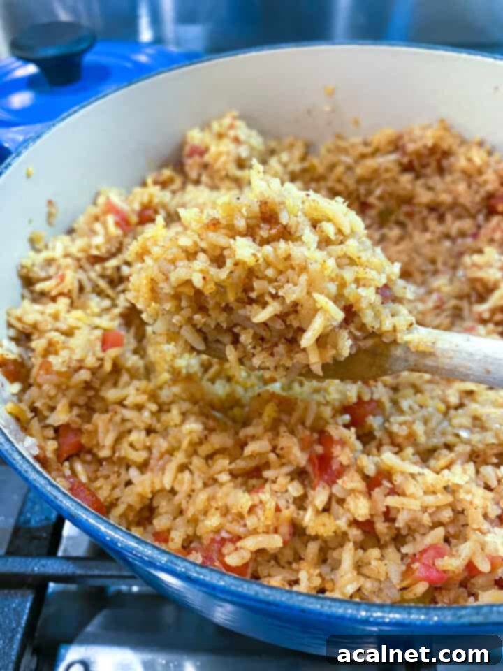 A pot full of cooked Mexican rice with a wooden spoon scooping out a serving.