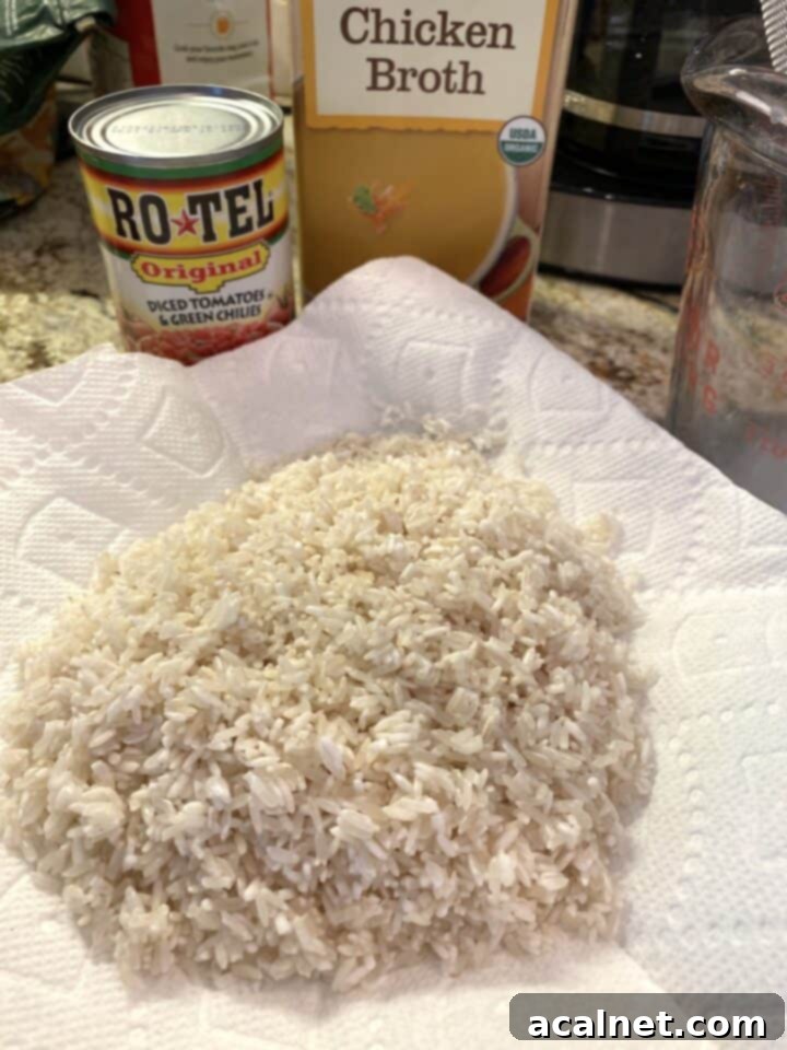 Rice drying a paper towel with canned tomatoes and boxed chicken broth in the background.