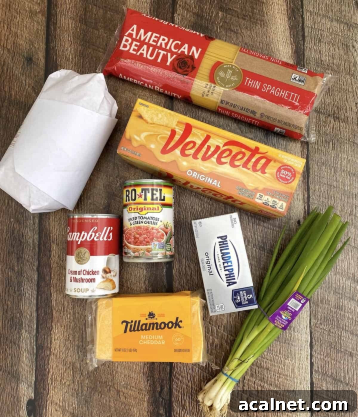 Ingredients for chicken spaghetti with Velveeta and Rotel spread out on a wooden plank.