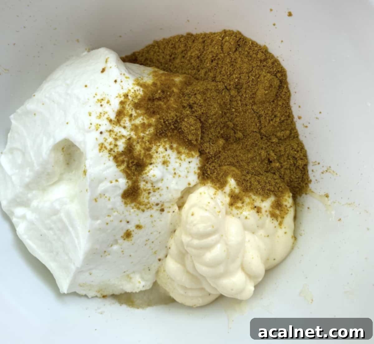 Curry powder on top of mayonnaise and non-fat Greek yogurt.