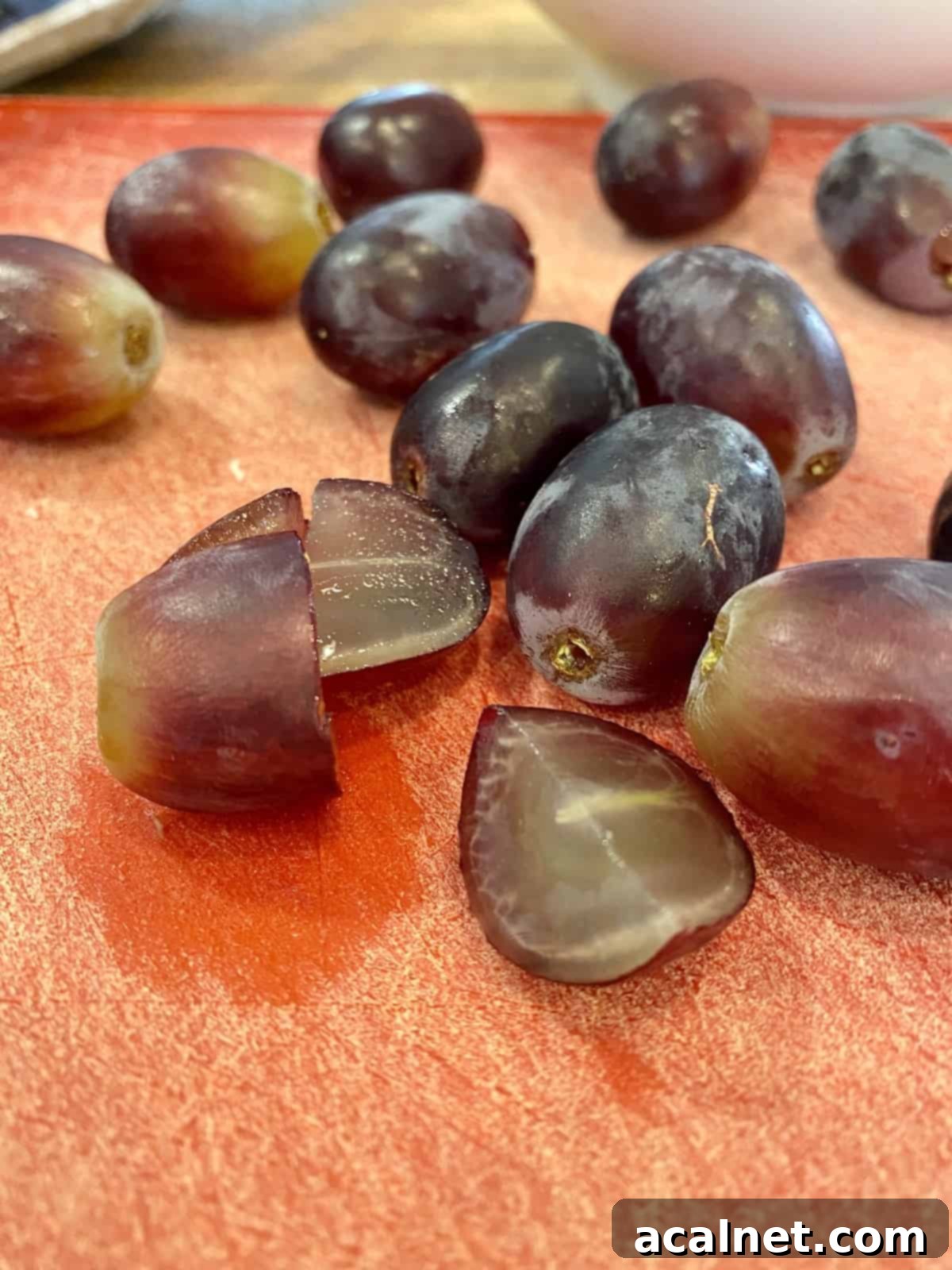 Grapes sliced in half on a cutting board.