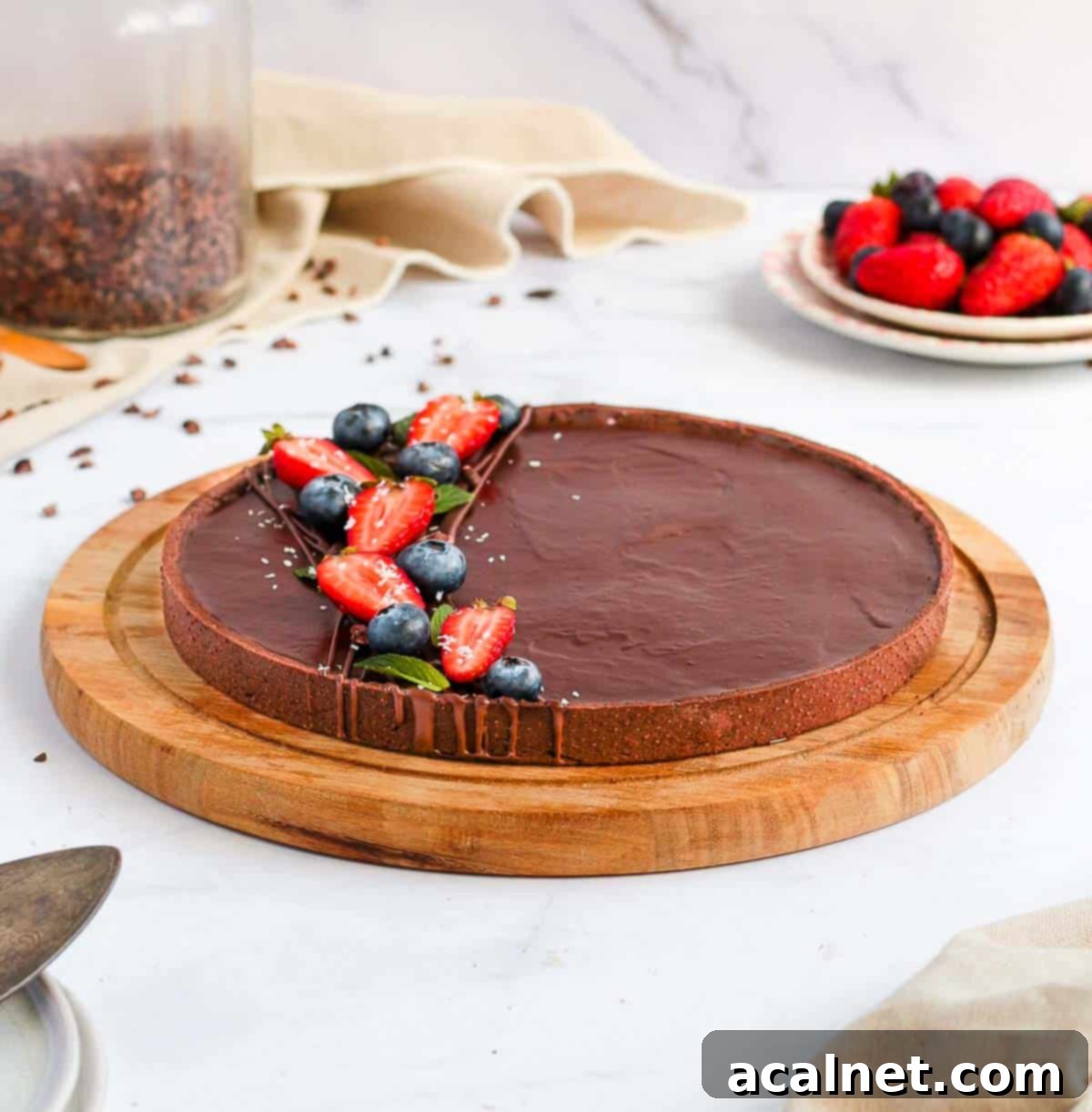 A stunning top-down view of the whole Chocolate Ganache Tart on a round wooden board, presented beautifully on a white surface.