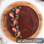 A beautifully presented Classic French Dark Chocolate Ganache Tart, viewed from above, resting on a round wooden board.
