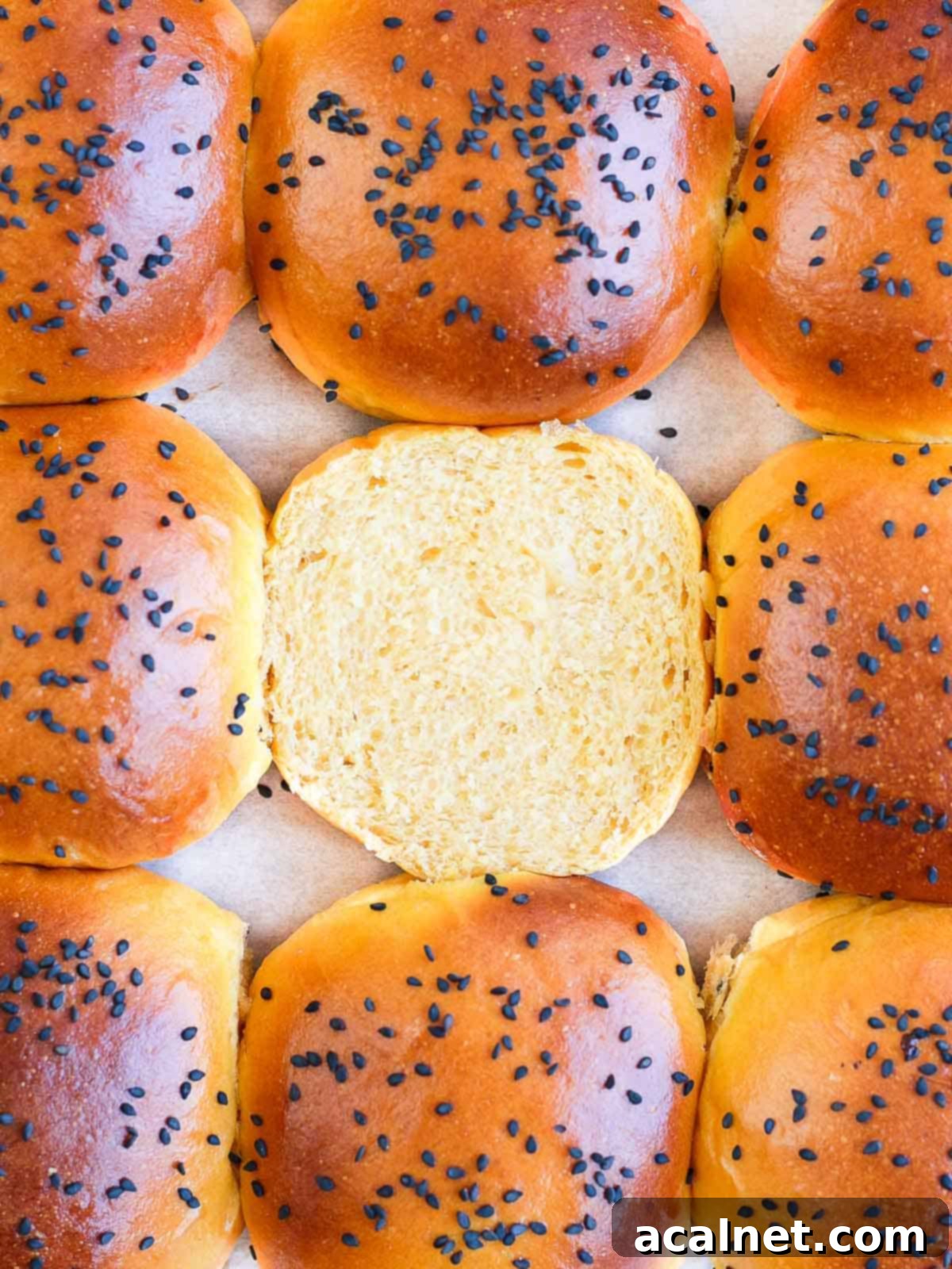 A close-up view of the soft, airy crumb of a sweet potato bun, resting on baking paper with a wooden board in the background.