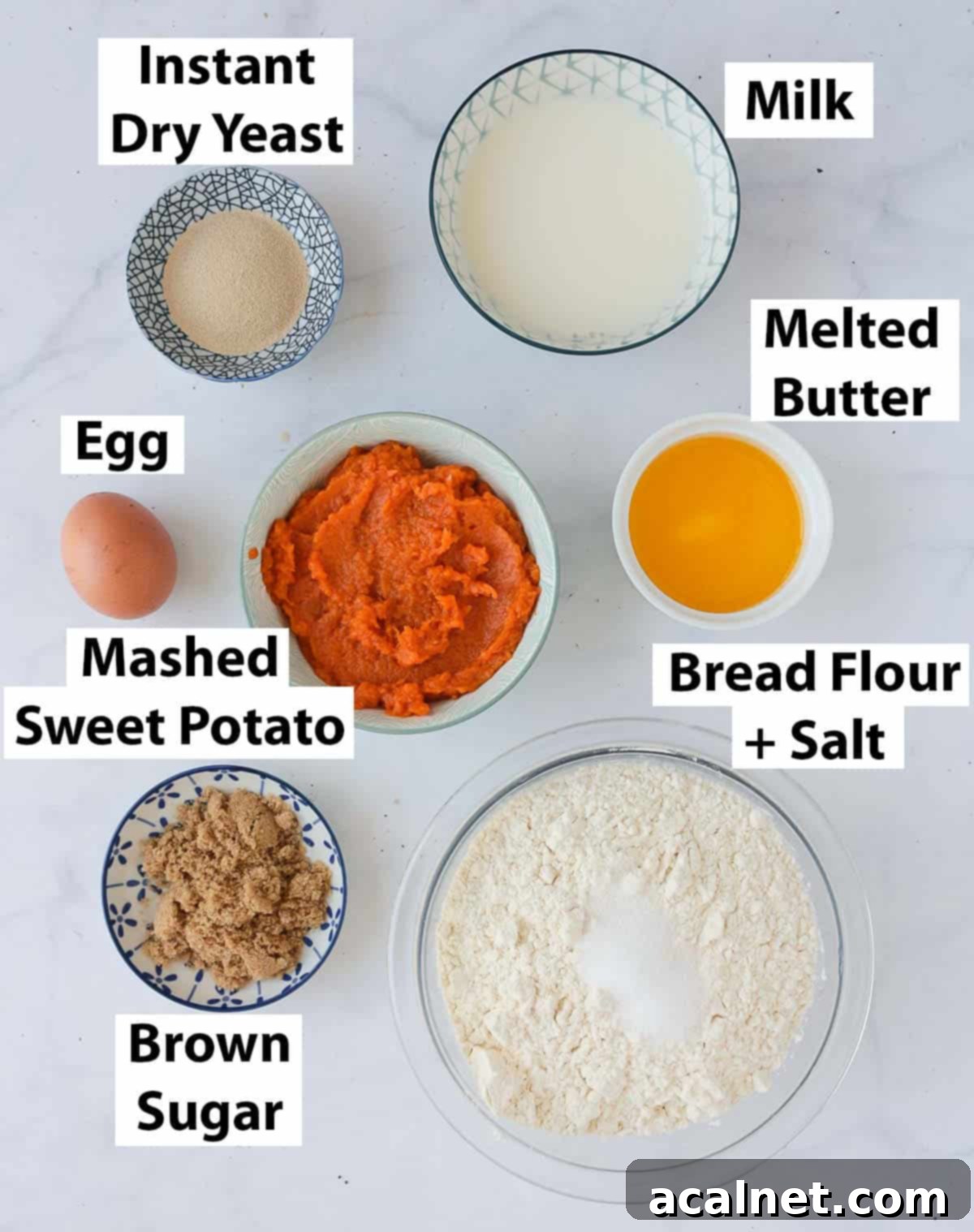 A collection of fresh ingredients for sweet potato buns, neatly arranged on a pristine white marble surface.