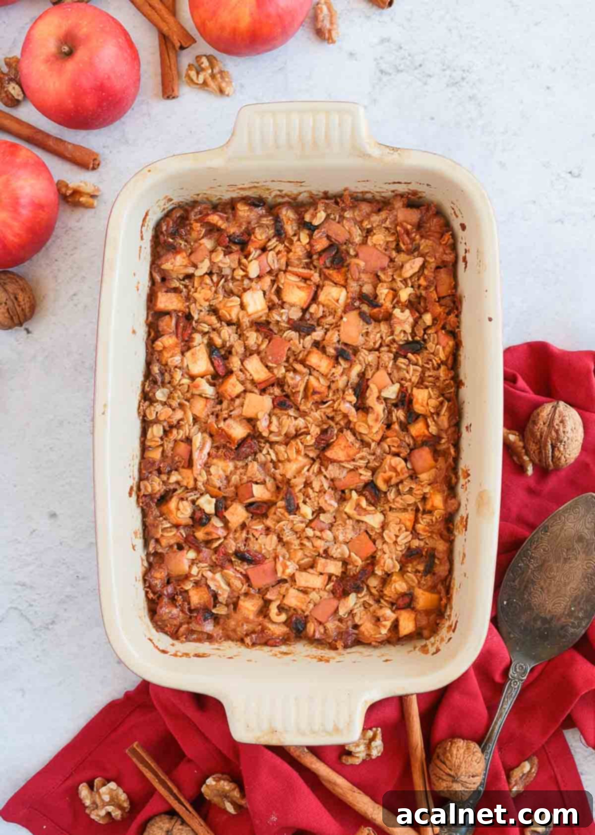 Baked Oatmeal in a ceramic dish from above surrounded by apples and a red napkin.