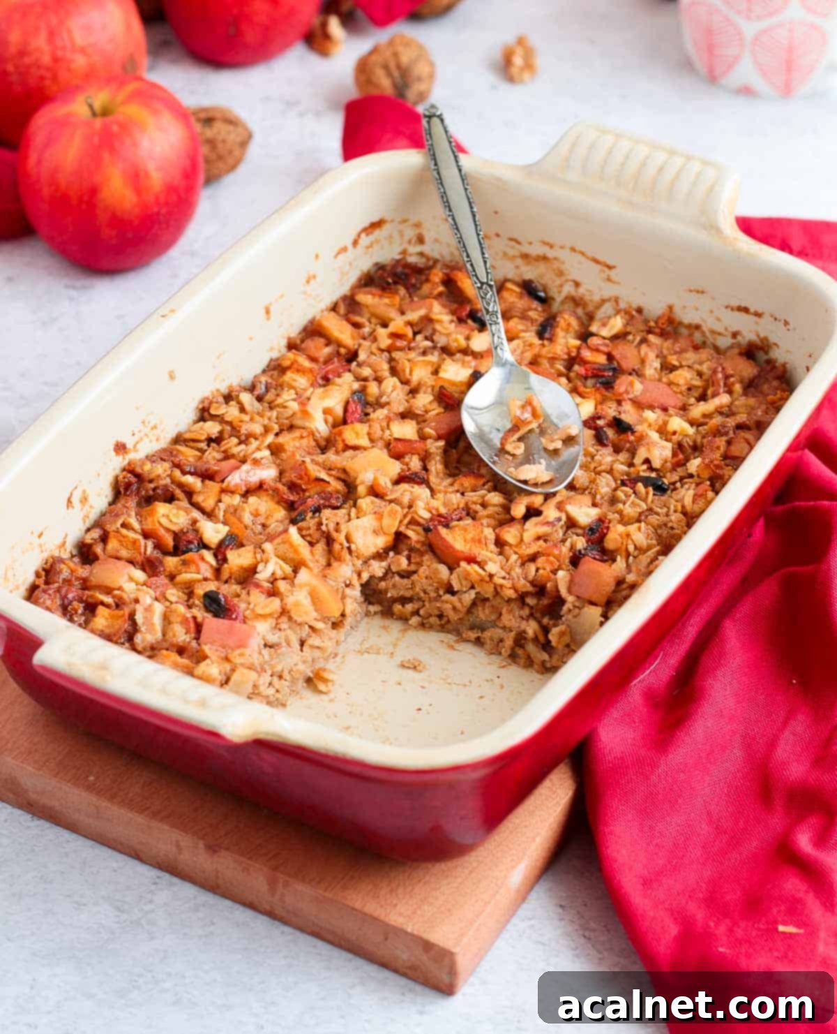 Baked Oatmeal in a white and red ceramic dish topped with a metallic spoon.