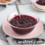 Blueberry Compote in a glass bowl over a pink plate.