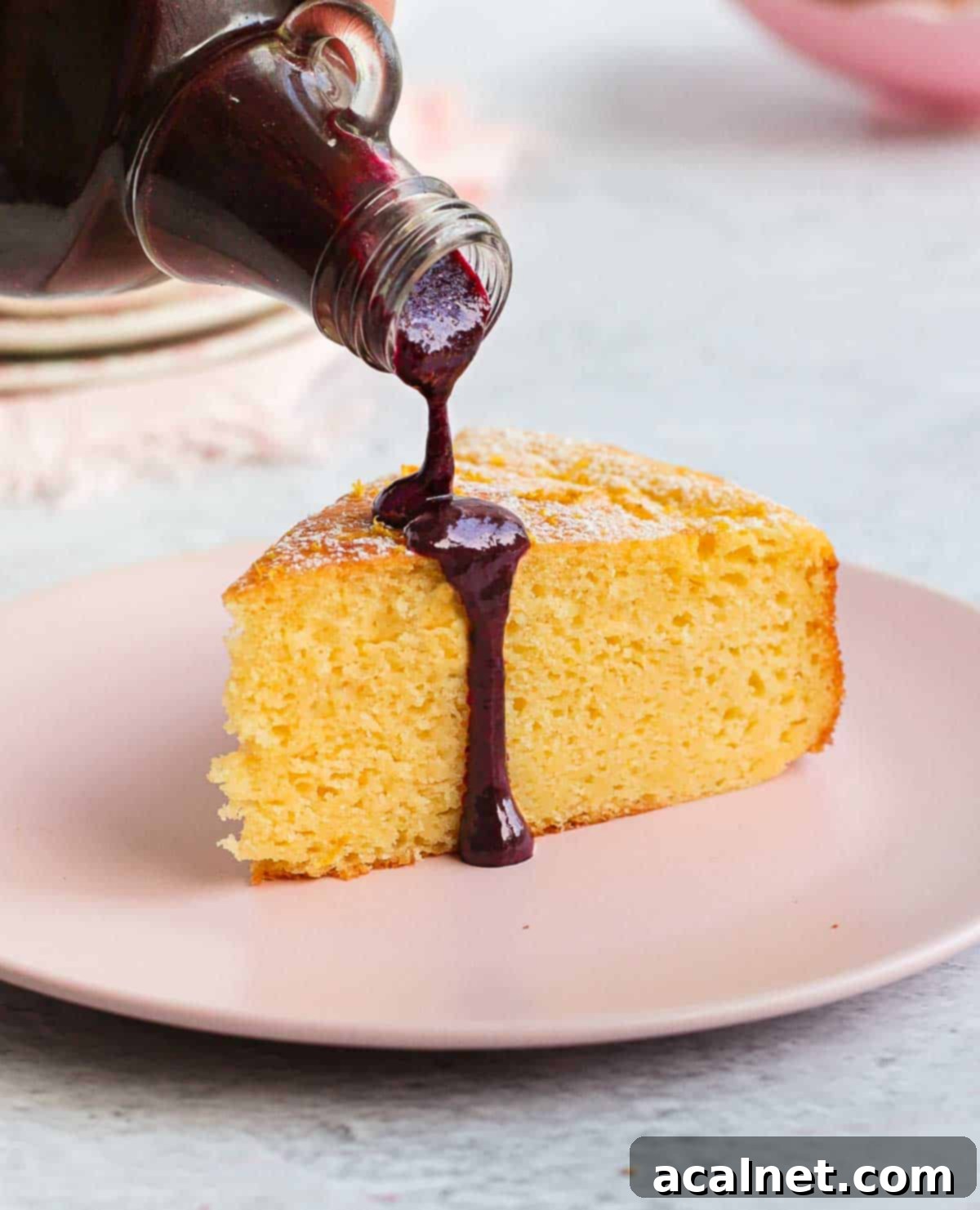 Pouring the vibrant, smooth blueberry coulis over a slice of cake, illustrating its perfect pourable consistency and rich color.