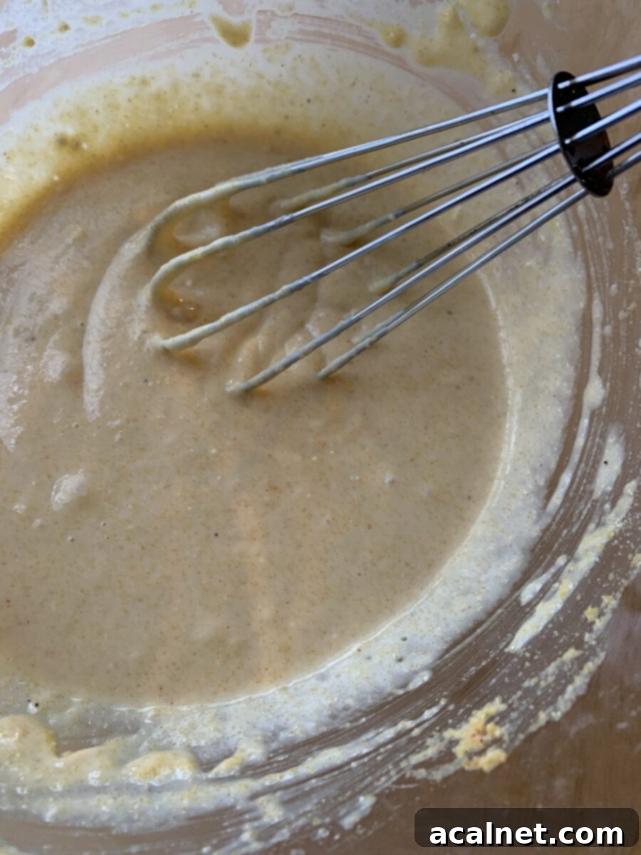 Raw corn dog batter in a mixing bowl with a whisk