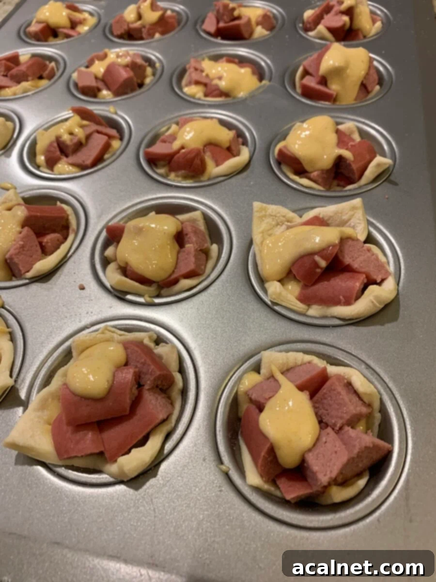 Uncooked corn dog nuggets in a mini muffin pan before baking