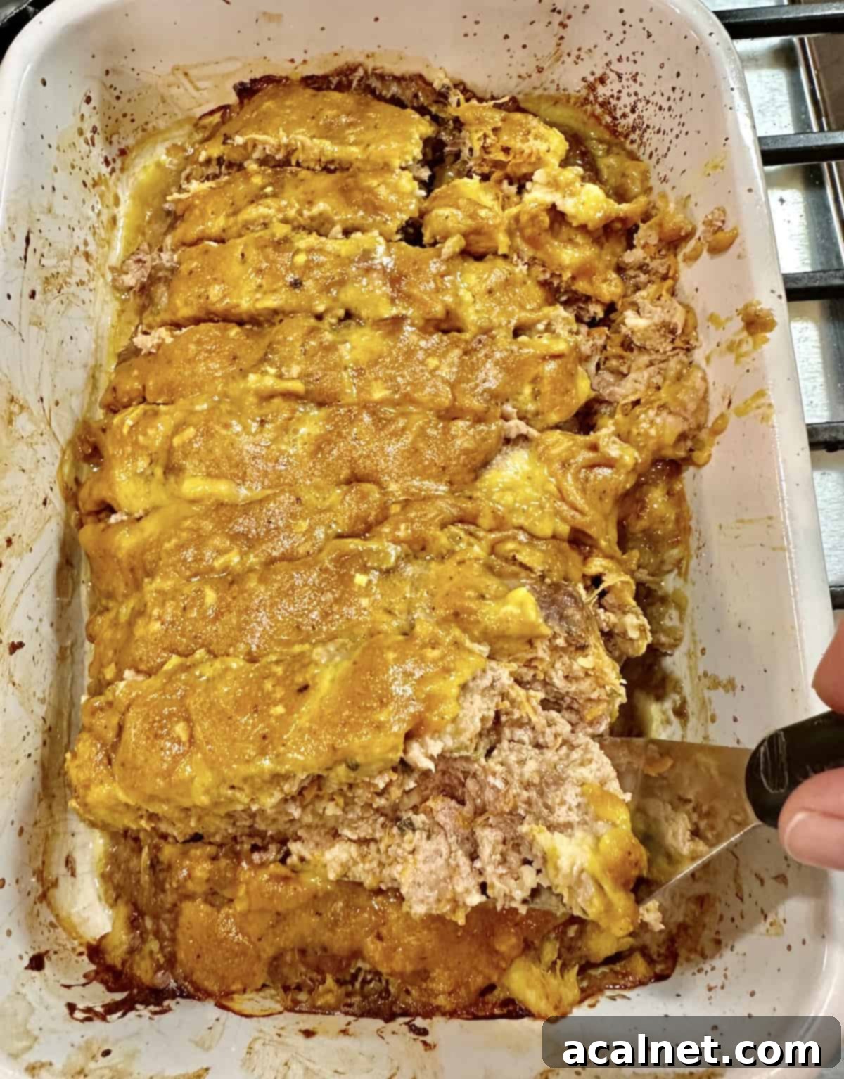 Meatloaf Beyond Ketchup 10 A baked meatloaf with mustard glaze on top, with a serving scooped out to show its interior.