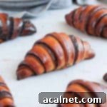 Close up on one chocolate rugelach on a grey surface.