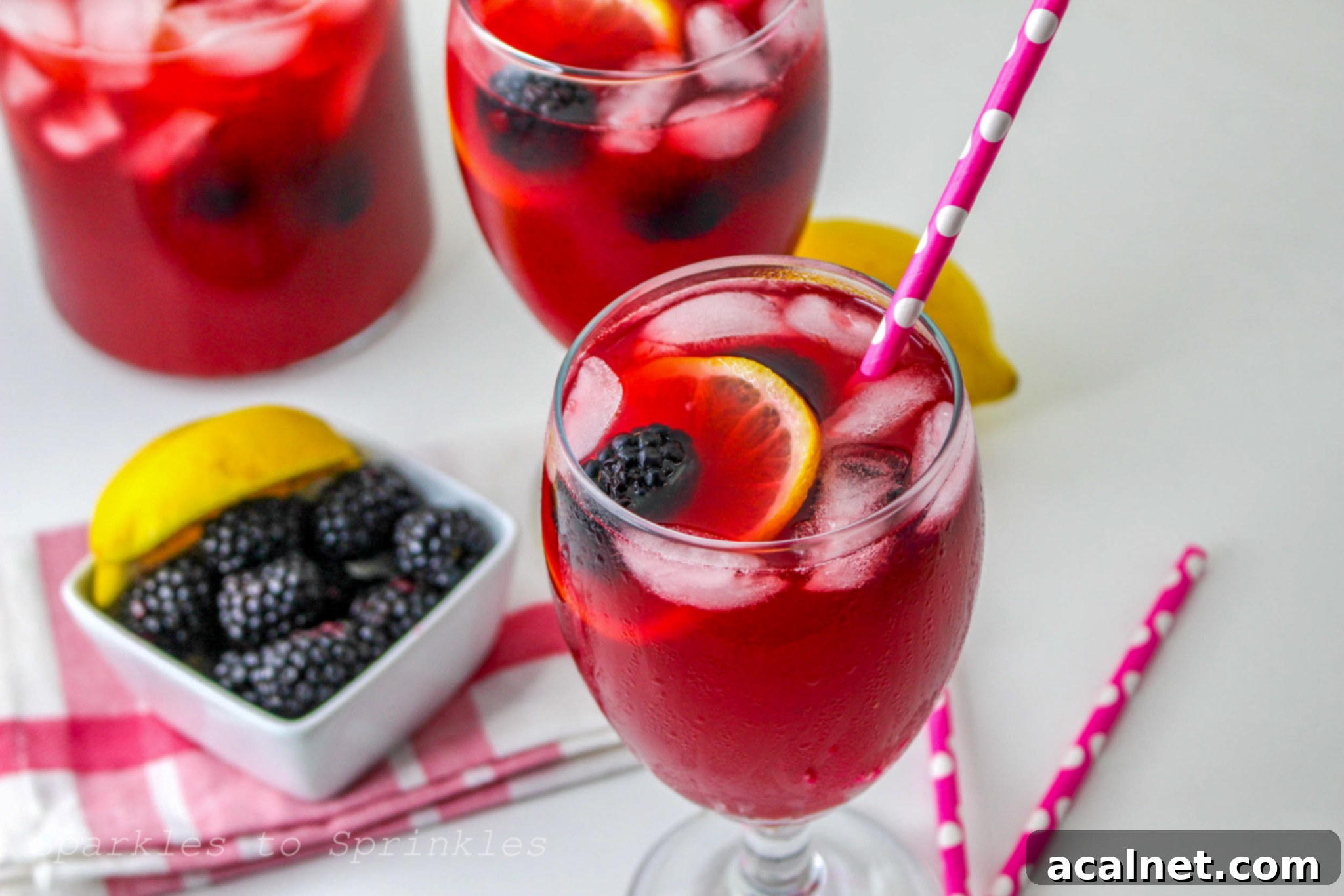 A pitcher of refreshing blackberry lemonade with lemon slices and berries.