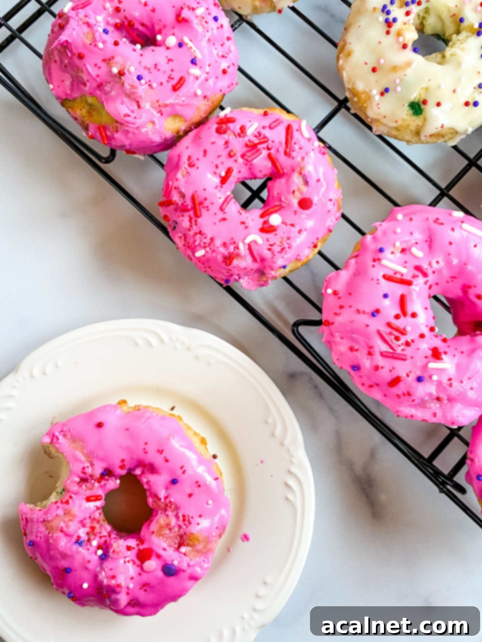 Light pink baked donuts with colorful sprinkles.