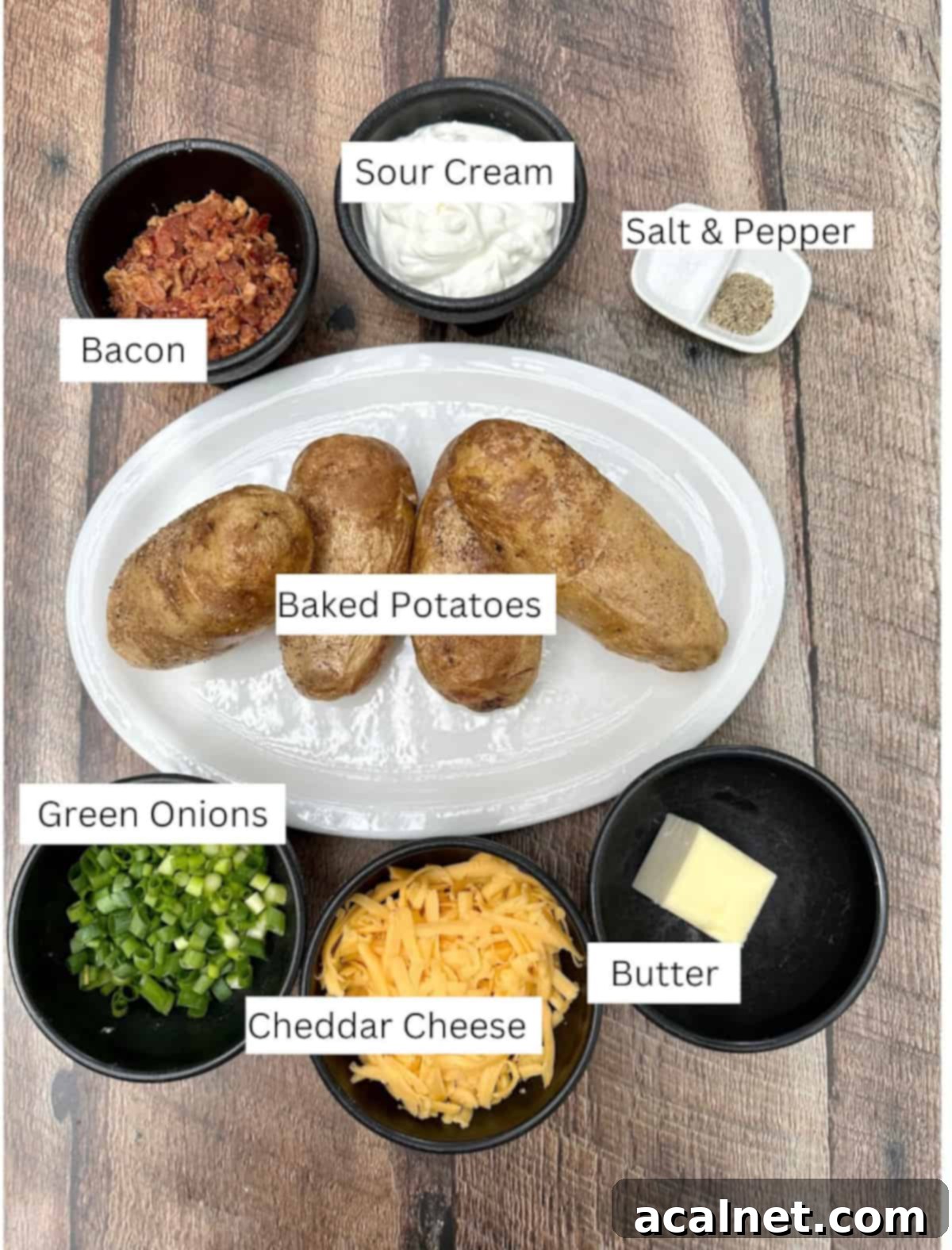 Ingredients for Twice-Baked Mashed Potatoes arranged on a wooden table and labeled.