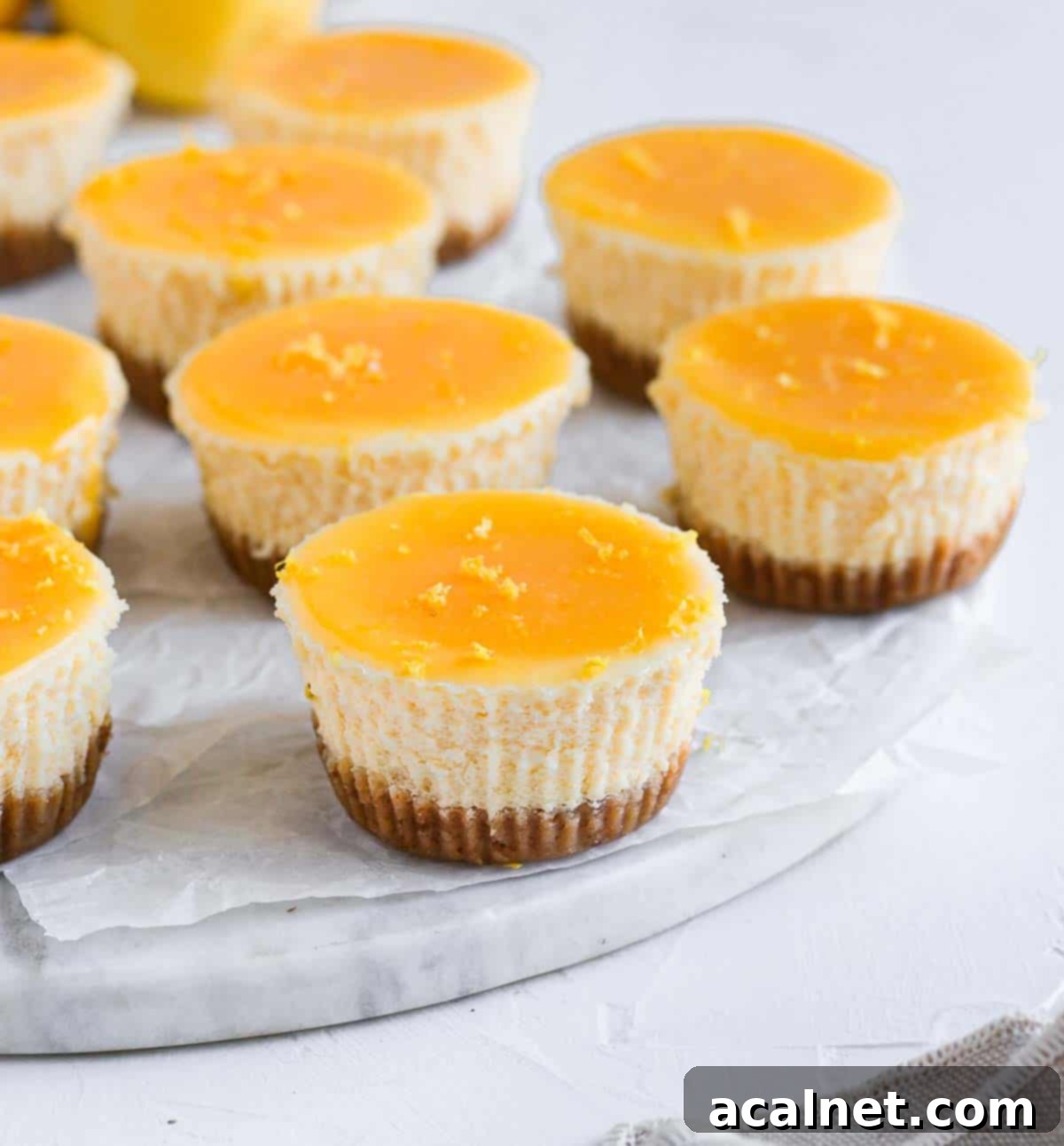 Zesty Mini Lemon Curd Cheesecakes 4 A single mini lemon cheesecake displayed on a round marble board, highlighting its smooth top and golden crust.