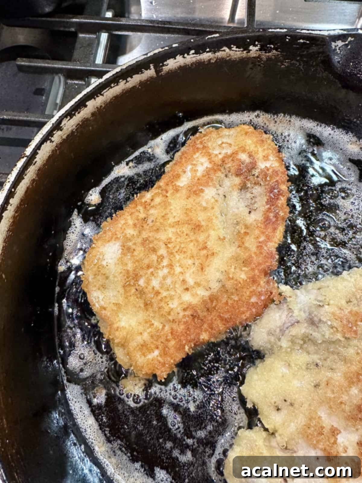 Chicken cutlets in hot oil in a skilled on the stove, sizzling to a golden crisp.