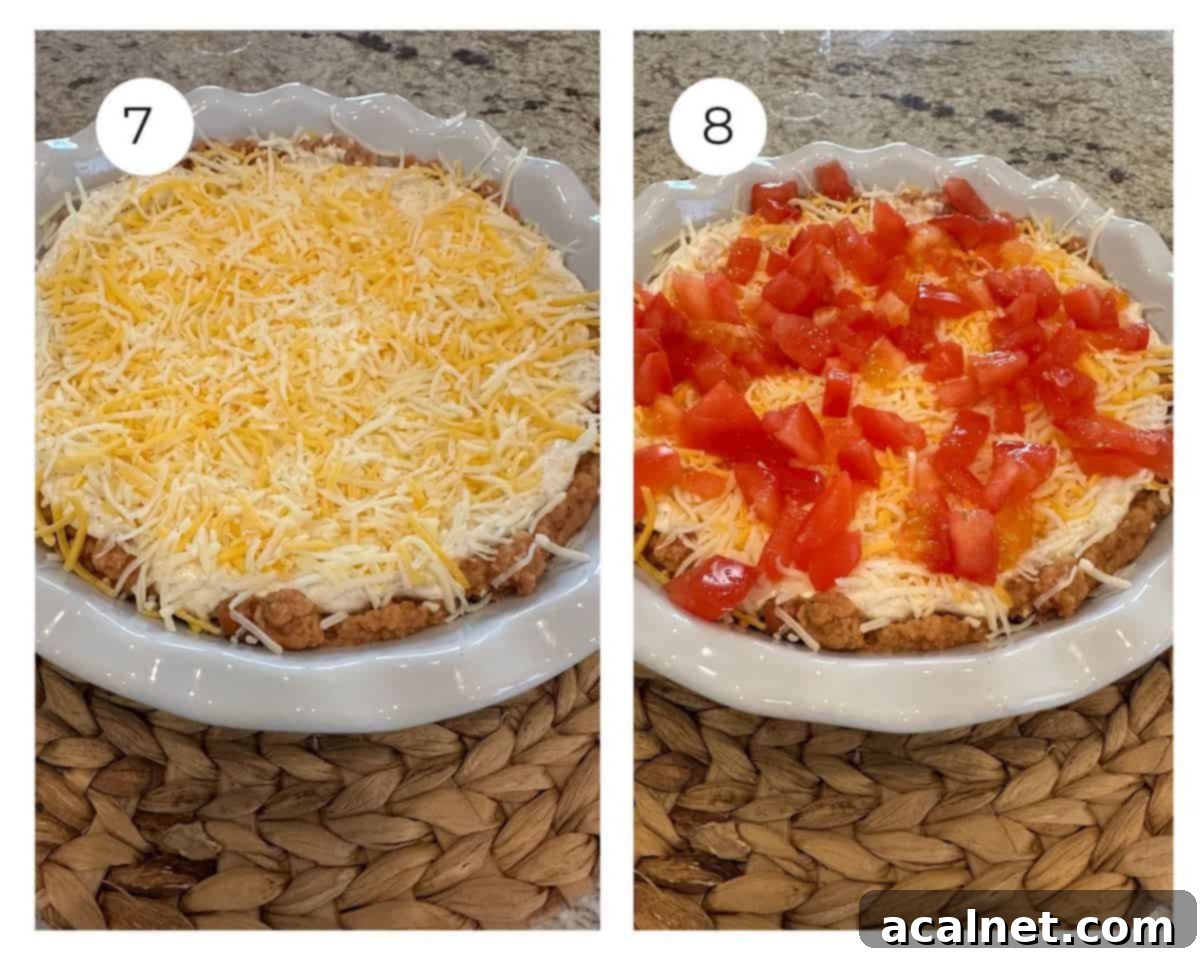 Taco dip with shredded cheese sprinkled on top, followed by diced tomatoes.