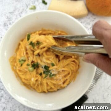 Tongs being used to scoop a serving of pasta.