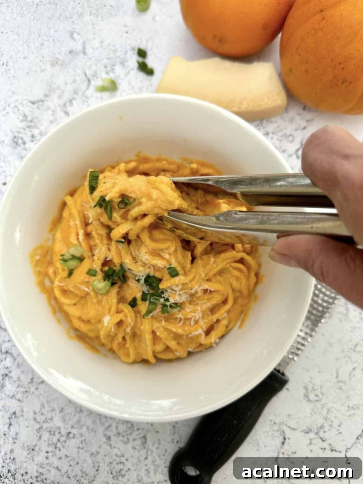 Tongs being used to scoop a serving of pasta.
