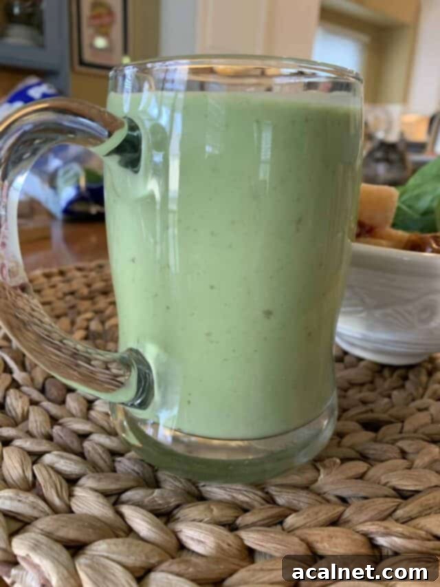 Sweet green smoothie in a glass mug, garnished with a slice of banana, invitingly presented.