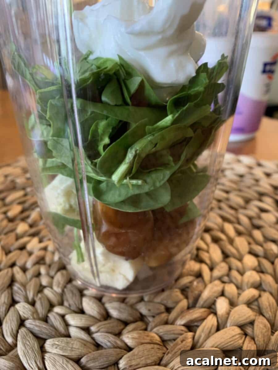 Sweet green smoothie ingredients, including yogurt, layered in a blender cup.