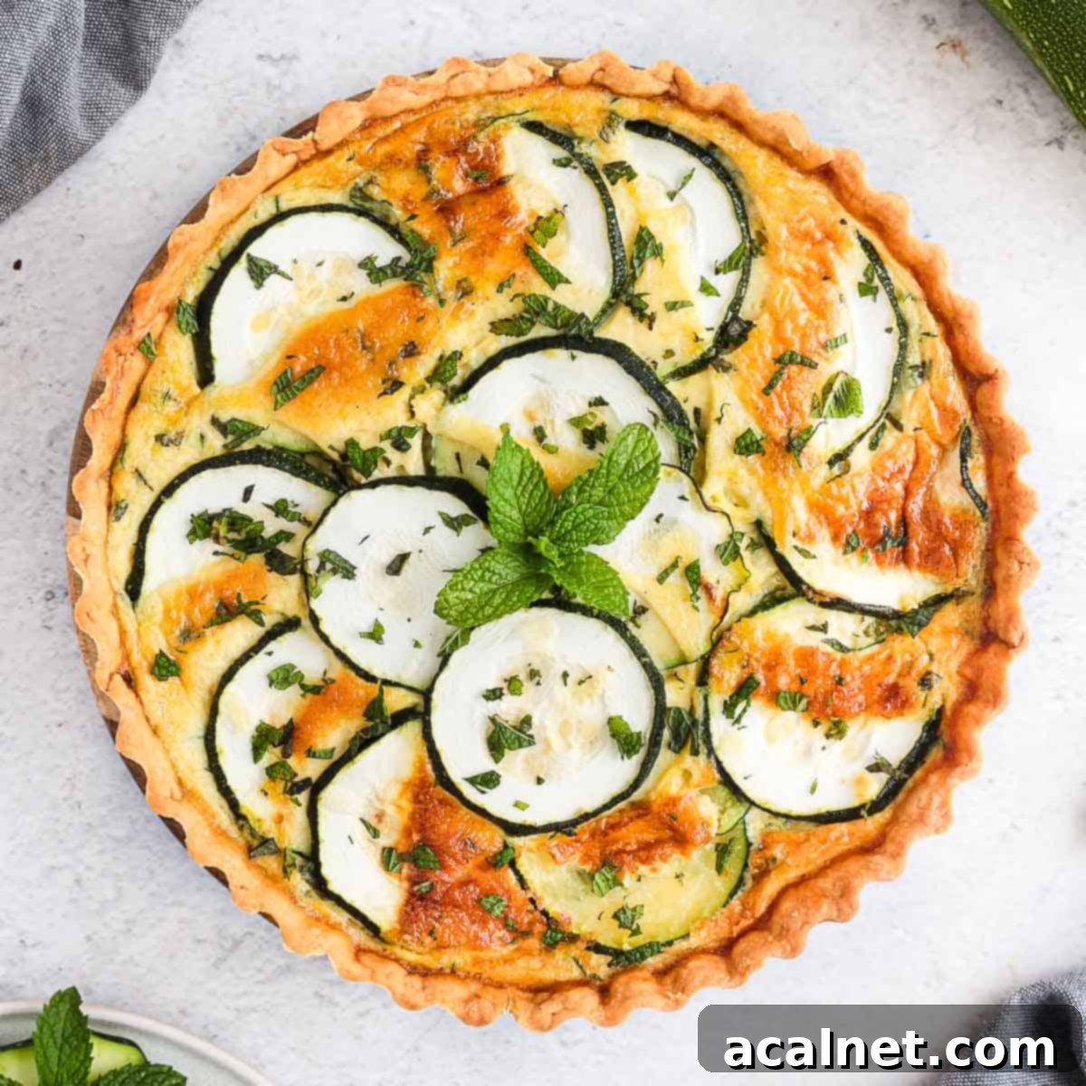 A beautifully baked Zucchini Quiche with Feta and Mint, seen from above, showcasing golden crust and vibrant green zucchini slices.