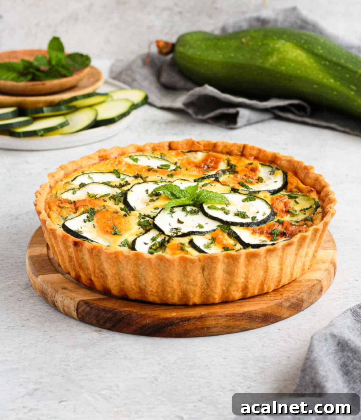 A baked Zucchini Quiche with Feta and Mint resting on a rustic wooden platter, ready to be served.