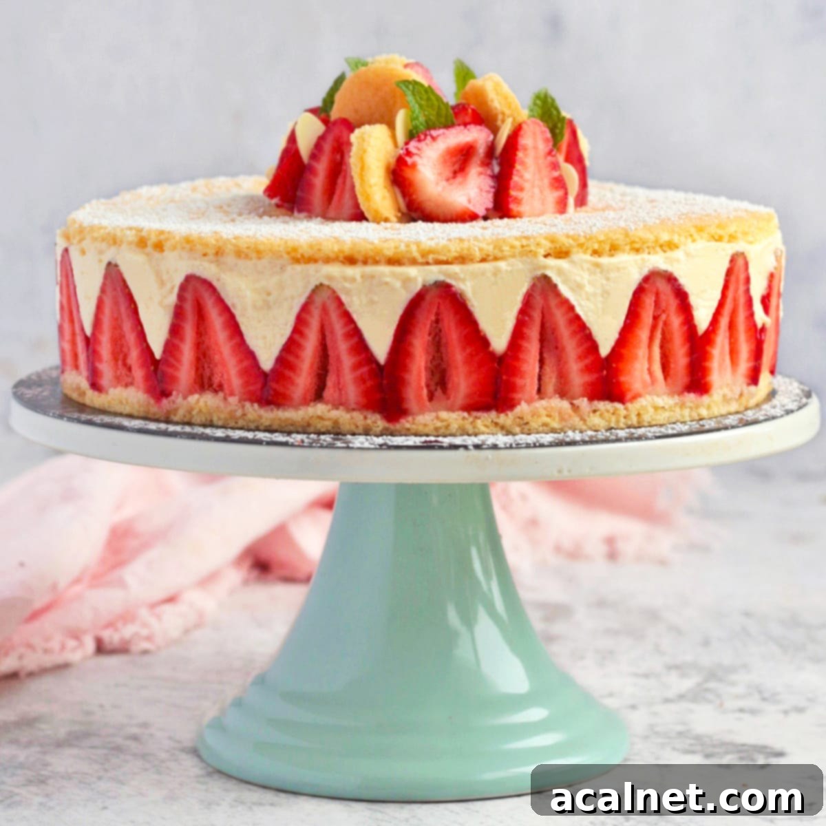 A classic Fraisier Cake with diplomat cream and fresh strawberries on a green cake stand.