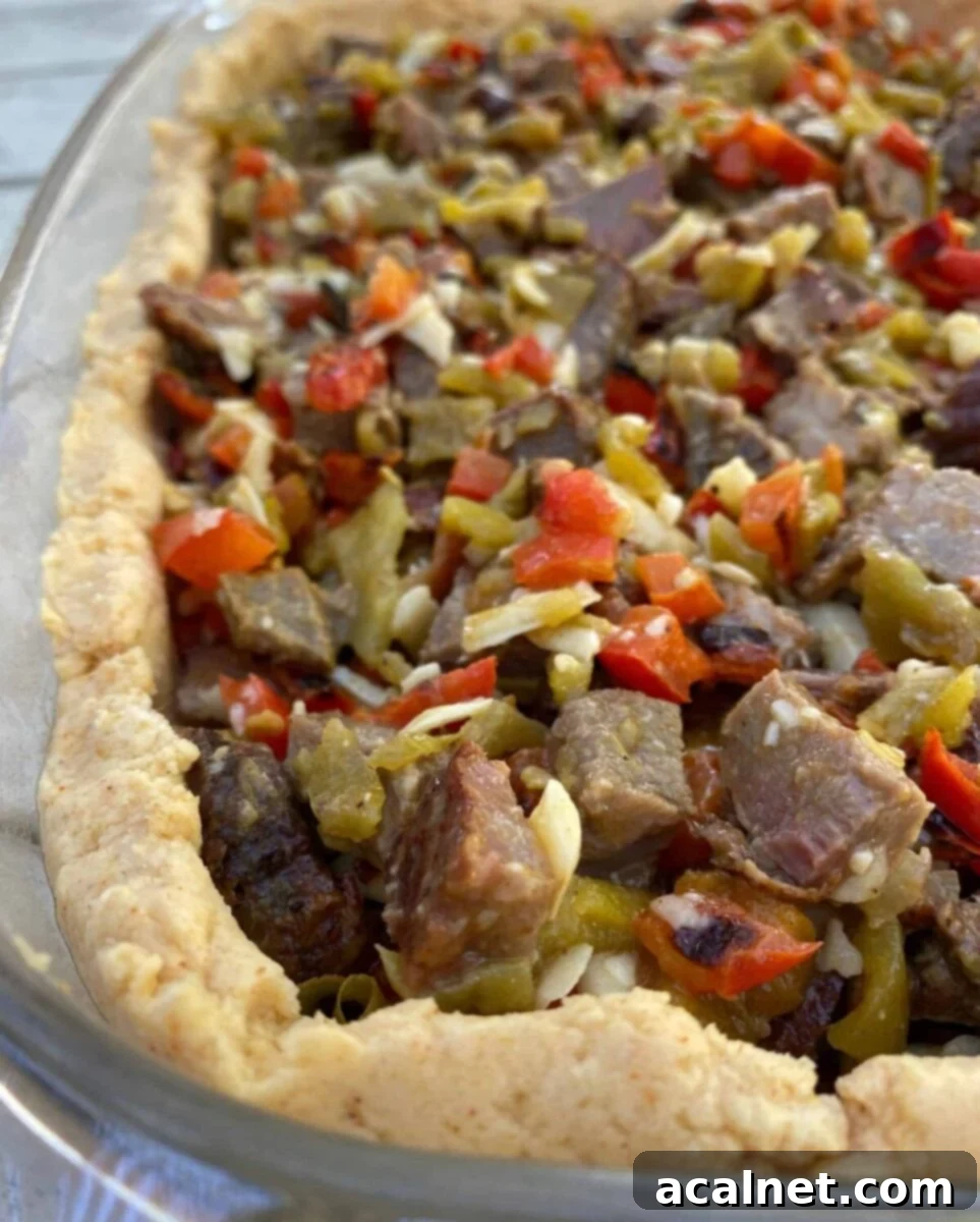 Diced beef with red peppers and green salsa in a tamale crust, all placed in a large glass dish, before being baked.
