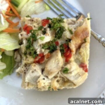 Chicken casserole on a plate with salad on the side and a fork on the plate.