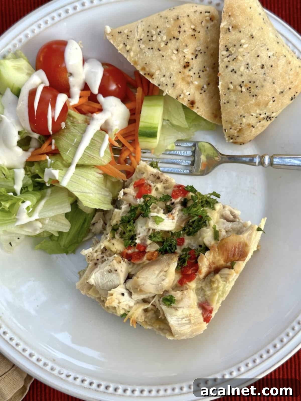Chicken casserole on a plate with rolls and a side salad.