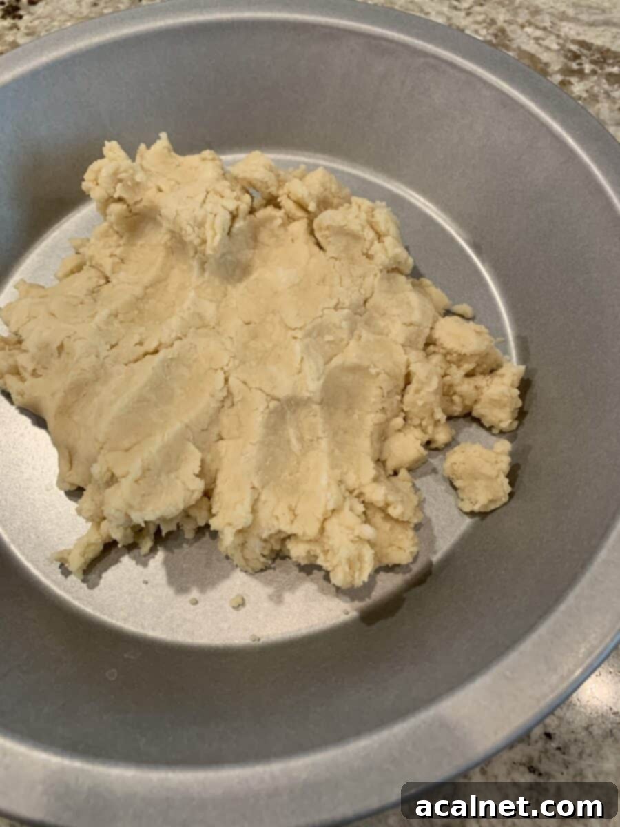 Unbaked pie crust dough in a pie plate, ready for the oven, demonstrating the pat-in-the-pan method.