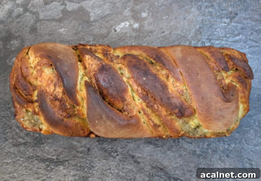 A slice of Pesto Mozzarella Babka Bread revealing the beautiful swirls of green pesto and melted white mozzarella.