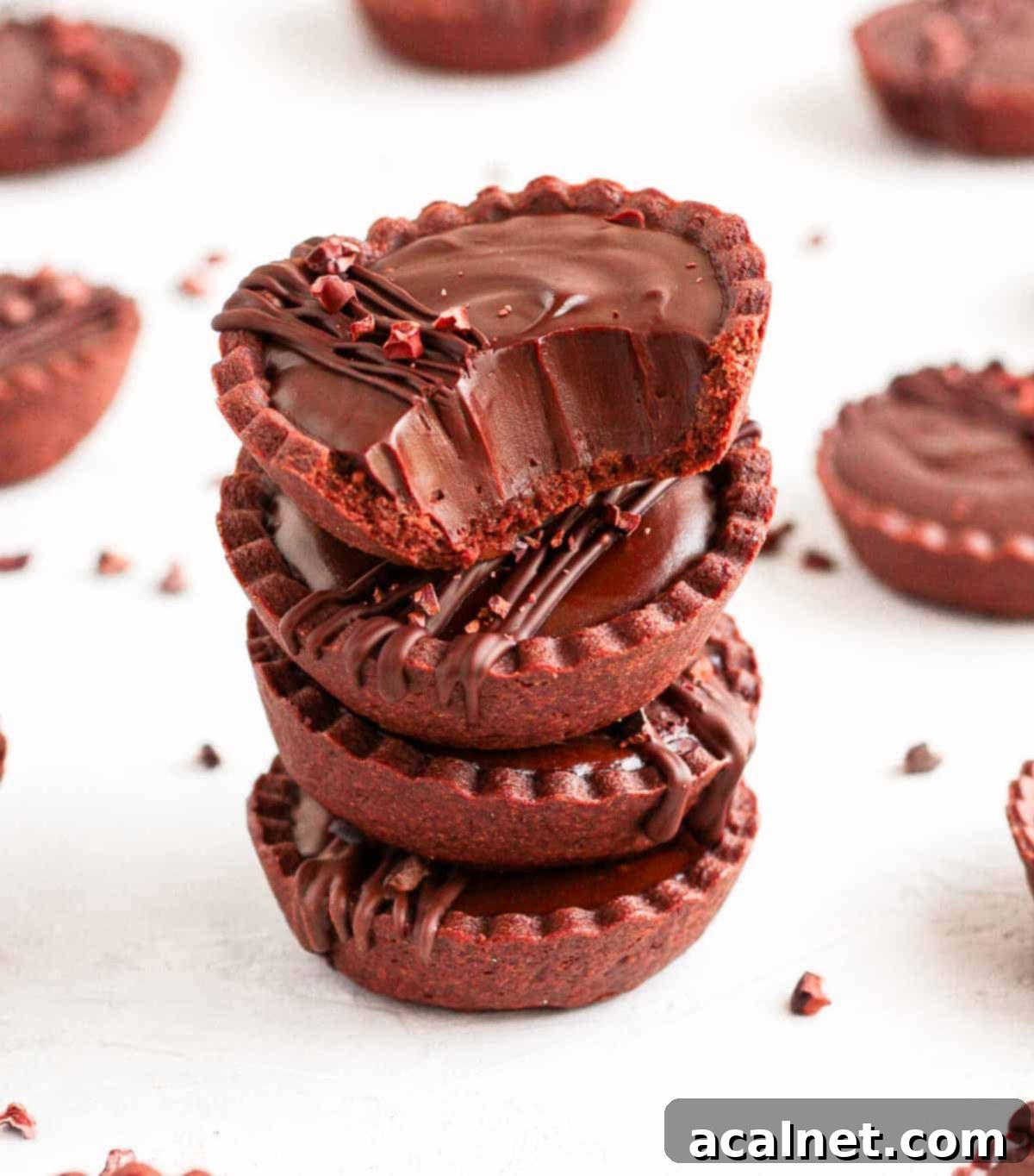 A bite taken off a tartlet sitting on top of a tart stack.