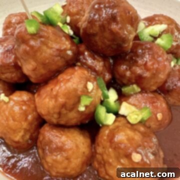 Sweet Heat Cranberry Jalapeño Meatballs 9 Meatballs in a serving bowl, garnished with fresh diced jalapeños.