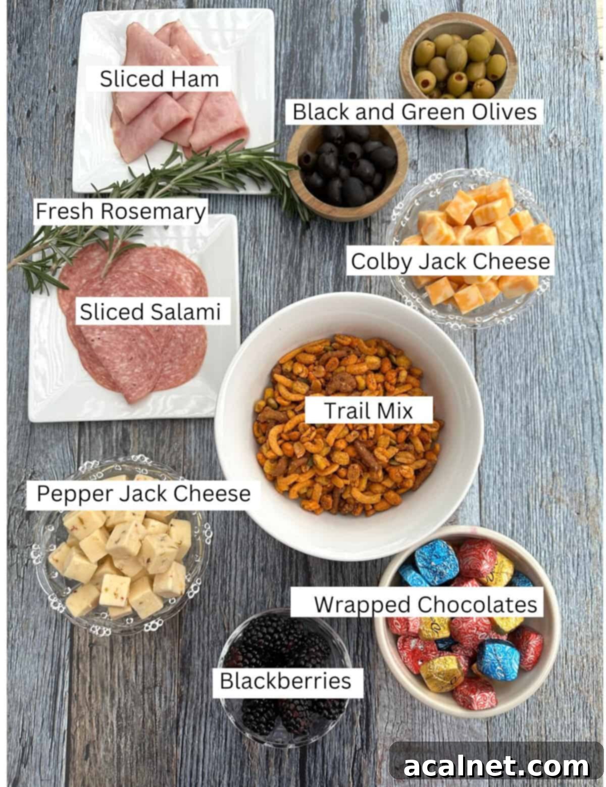 Ingredients for charcuterie cups labeled and on wooden planks.