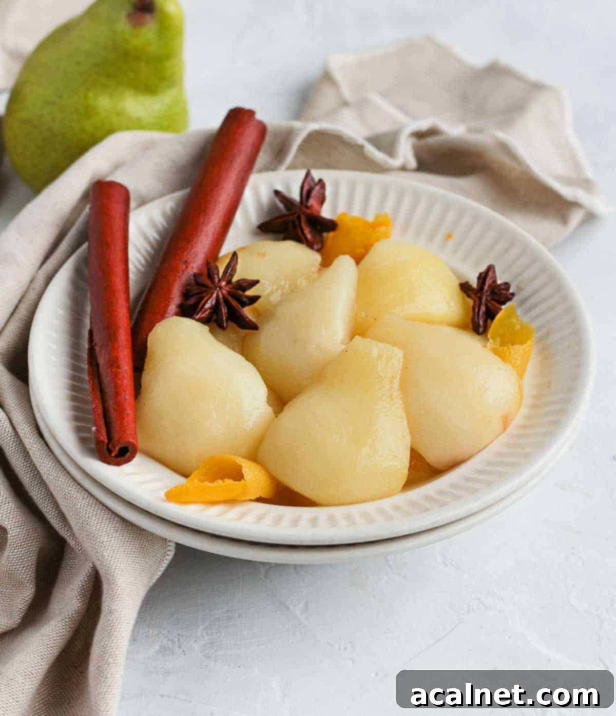 Cooked pears in a white bowl with beige napkin.