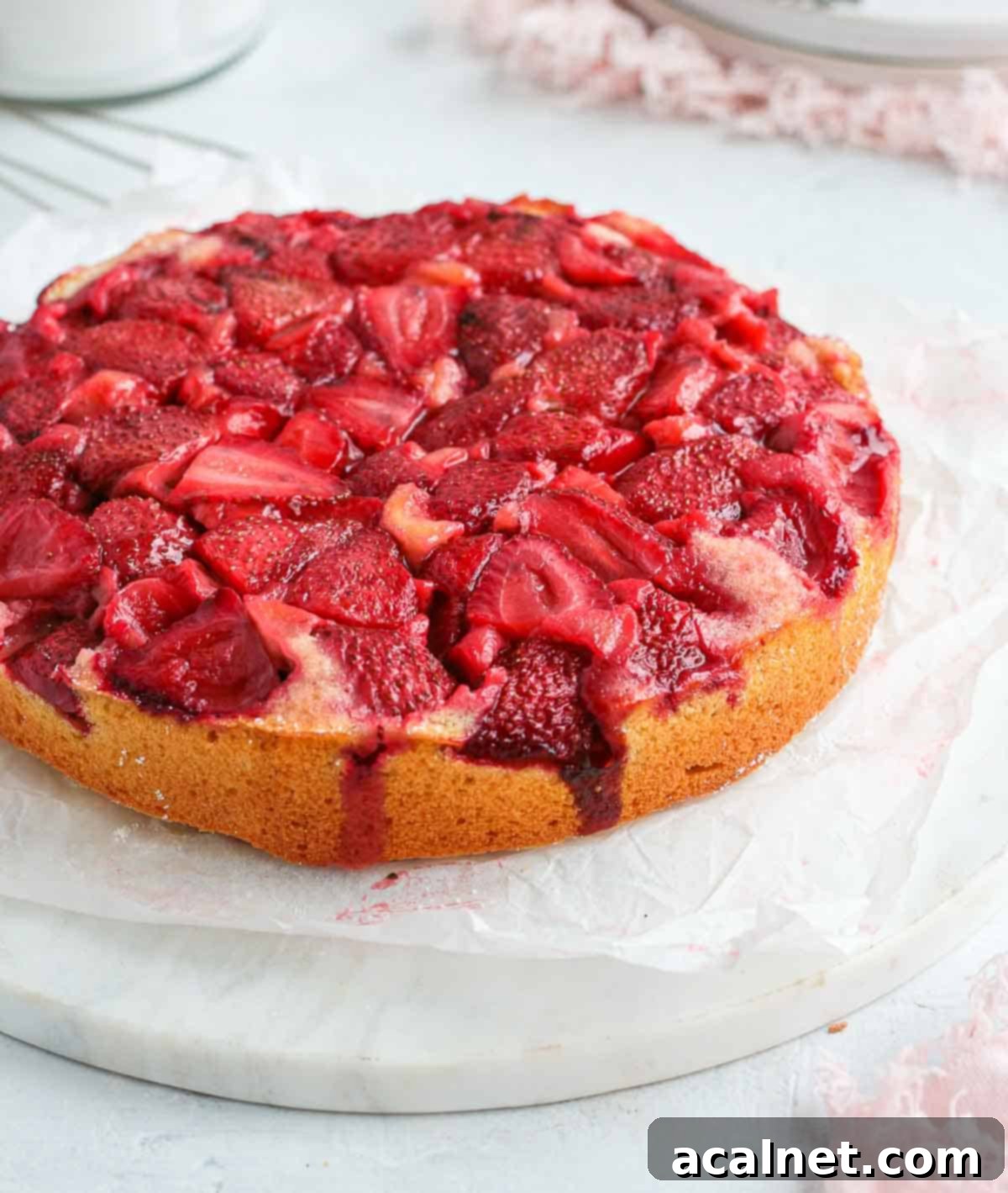 Close up view of the roasted, caramelized strawberries on top of a cake.